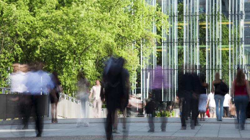 People walking outside in front of an office building.