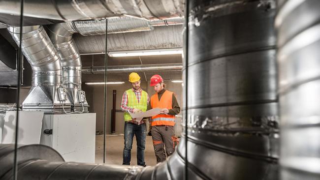 Workers making final touches to HVAC system. HVAC system stands for heating, ventilation and air conditioning technology. 